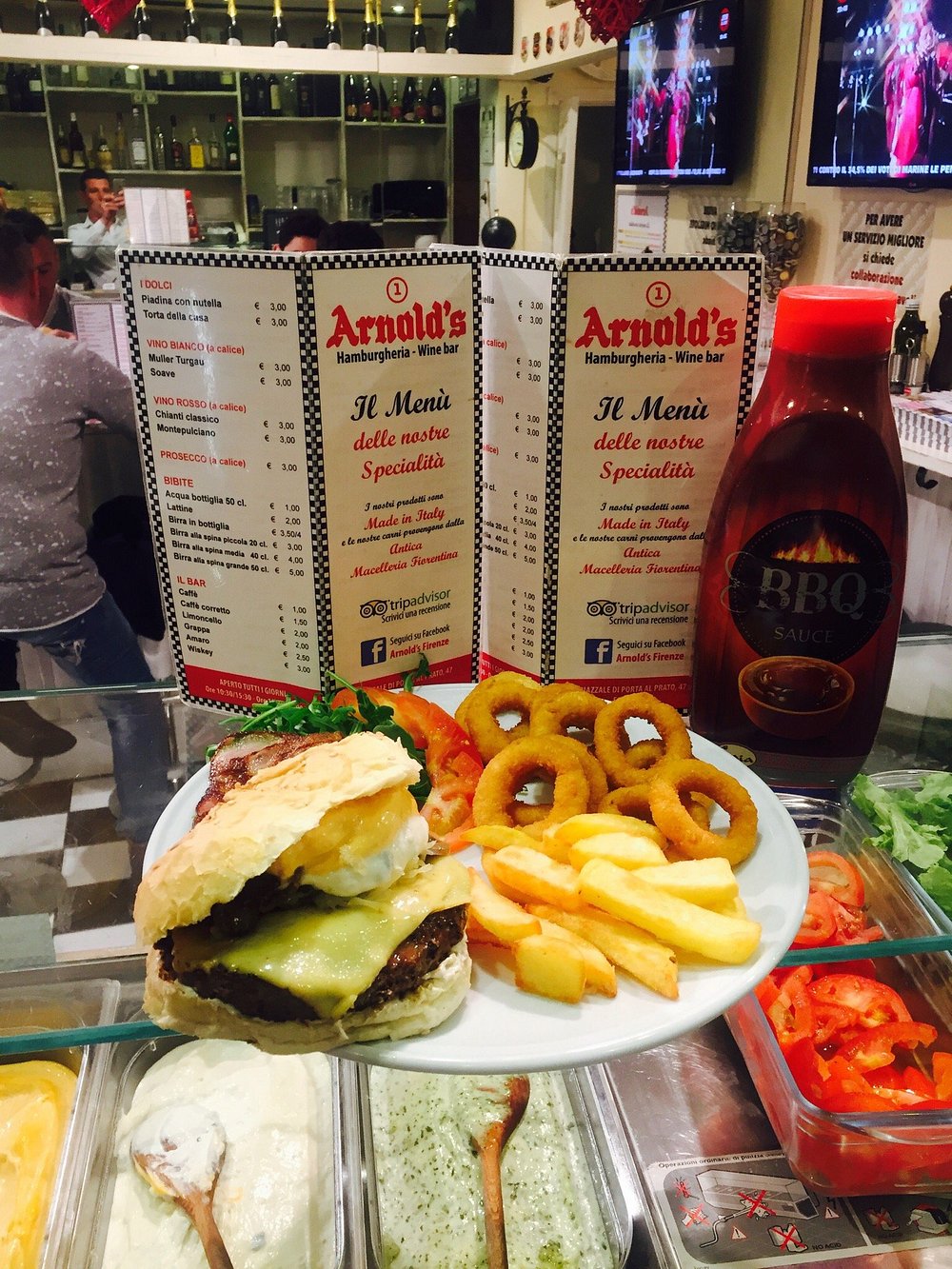 Il bancone di Arnold's con i menù e un piatto di hamburger, patatine e anelli di cipolla