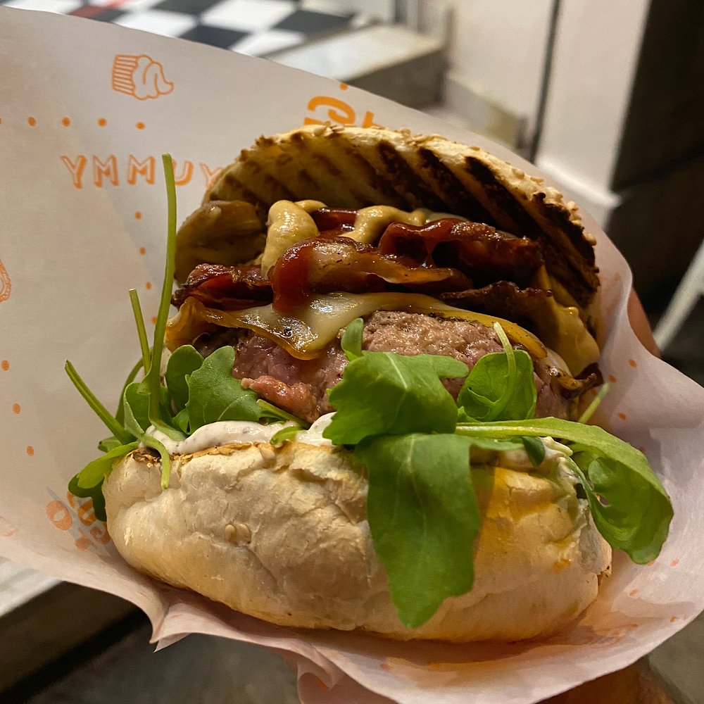 Panino con hamburger, rucola e bacon avvolto nella carta